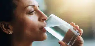 Femme buvant un verre d'eau pour rester hydratée